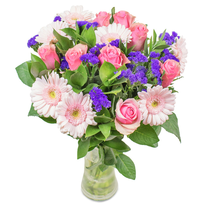 This artistically arranged bouquet, presented in a clear glass vase on a pristine white background, epitomizes floral elegance in Southgate style. Seven to nine medium pink roses are the centerpiece-petals tightly curled or gently blooming, showcasing a mesmerizing spiral. These roses are complemented by five to seven pale pink gerbera daisies, whose large, radiating petals and almost-white centers reflect the subtlety of spring in Arnos Park. Vivid clusters of purple statice or limonium are scattered throughout, creating an exuberant interplay of color and texture-much like the vibrant plantings found in local Southgate gardens. Lush, deep green foliage anchors the florals, enhancing the vivid beauty and freshness while echoing the neighborhood's leafy lanes. The transparent vase reveals the stems and water within, reinforcing an impression of natural abundance and freshly-cut delight, perfect for a surprise delivery to The Green or a heartfelt gesture anywhere in Southgate. Suitable for birthdays, anniversaries, Mother's Day, or as a decorative centrepiece, this composition radiates celebration, joy, and tenderness, crafted by hands deeply familiar with Southgate's unique floral preferences.